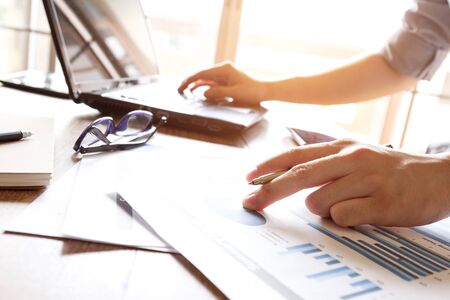 business man analyzing graph and chart document on office deskの写真素材