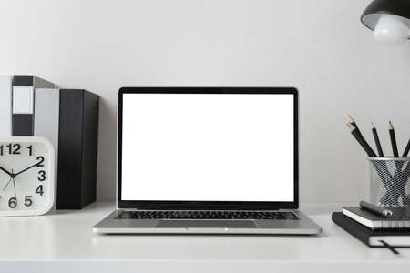 Modern contemporary workspace with blank screen laptop computer with office supplies and stationery...