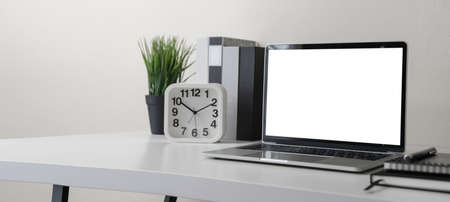 Modern contemporary workspace with blank screen laptop computer with office supplies and stationery...