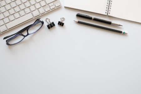 top view of modern workspace with computer keyboard and office supplies on white desk with copy space