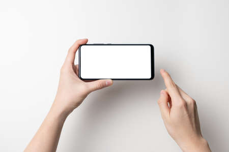 hand holding black mobile phone with white screen isolated on white background - clipping path includedの写真素材