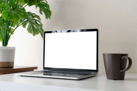 Laptop computer with blank screen for mockup on modern contemporary workspace white desk with coffee cup and office supplies. Home office workplace.の写真素材