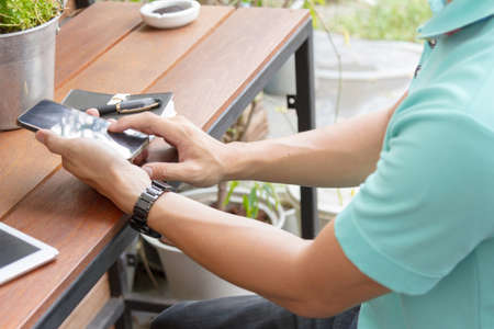 man using mobile phone on wooden table, outdoor scene