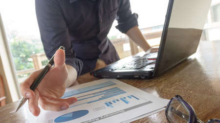 business man working with analysis graph chart document and using laptop computer at office table - business and finance analysis conceptの写真素材