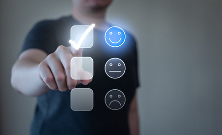 Young man pressing happy smiley face emoticon button on virtual touch screen. Customer service satisfaction evaluation concept.の写真素材