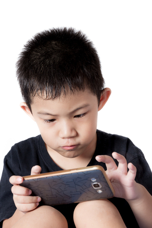 Little looks at play phone. Playing on a smartphone. Isolated on white background.の写真素材