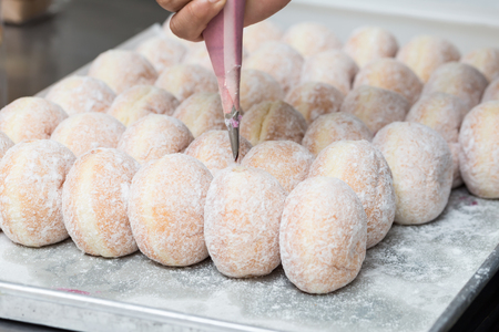 business bakery closeup hand work fresh donut jam backgroundの写真素材