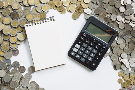 Business finance concept notebook paper and calculator on coins backgroundの写真素材