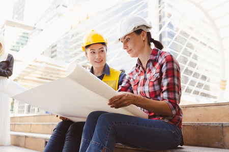 Engineers two woman working on plan building construction with paper in city