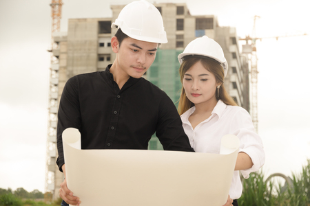 asian men and women engineers work on plans construction  in siteの写真素材