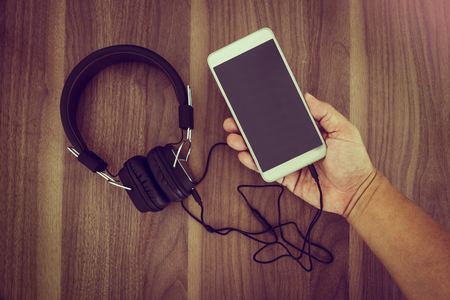 Smartphone and headphone on wooden background for listen to musicの写真素材