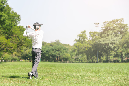Asian men playing golf. men play golf while standing on fieldの写真素材