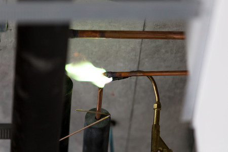 An industry worker welds to join the copper pipe of an air conditioner