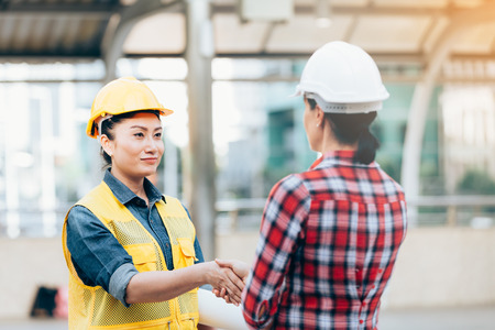 Engineers two woman shaking hands working on plan building construction in cityの写真素材
