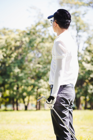 Asian men playing golf. men play golf while standing on fieldの写真素材