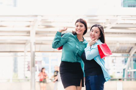 Beautiful girls and friend in city holding shopping bagsの写真素材