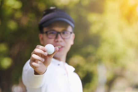 Asian men playing golf. men showing golf ball in hand standing on fieldの写真素材