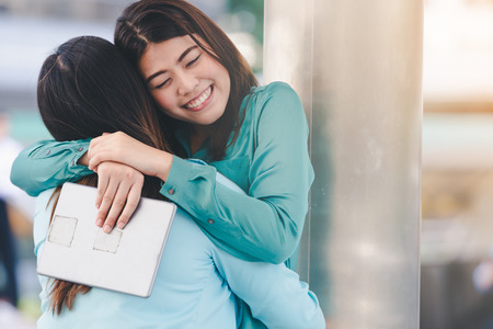 Portrait of happy asian women hugging each friend outdoor city backgroundの写真素材
