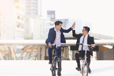 Asian handsome young businessmen talking while riding bicycles in cityの写真素材