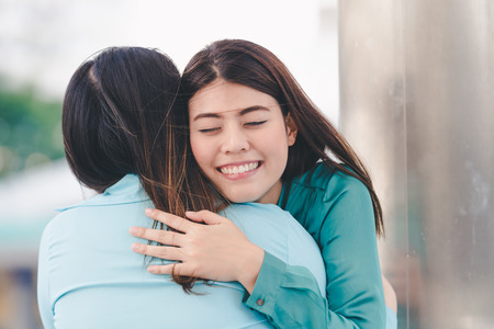 Portrait of happy asian women hugging each friend outdoor city backgroundの写真素材