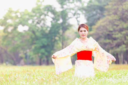 Asian young girl wearing a kimono in natural green grass.の写真素材
