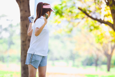 Asian couple playing golf. Man teaching woman to warm up while standing on fieldの写真素材
