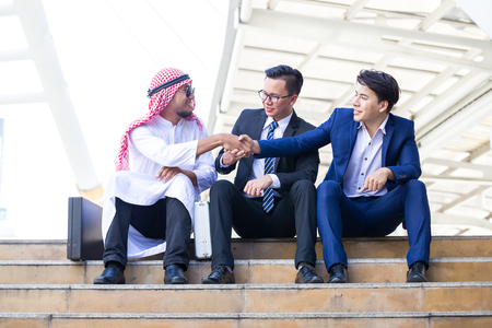 Arab shaking business men sitting working in the cityの写真素材