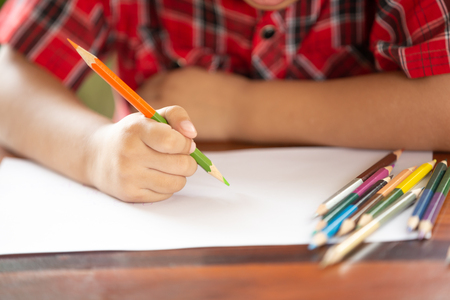 Asian little boy use color pencil writing on white paperの写真素材