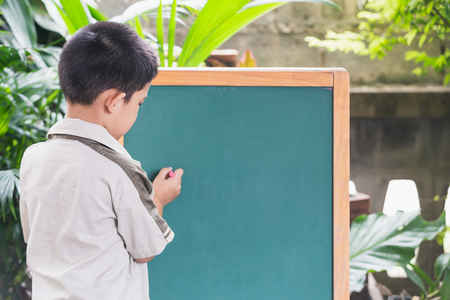 Asian little boy points hand write
 on blackboardの写真素材