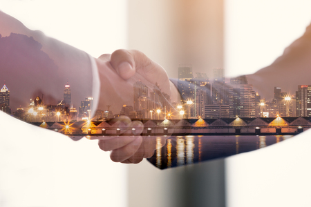 Close up of handshake double exposure night cityscape in hand, team work conceptの写真素材