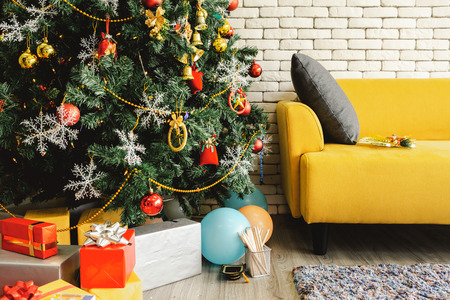 Christmas tree in room interior design and yellow sofa background brick wall Xmas tree decorated by...
