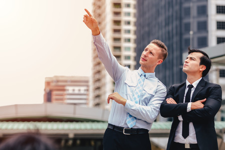 Two business men standing looking in cityの写真素材
