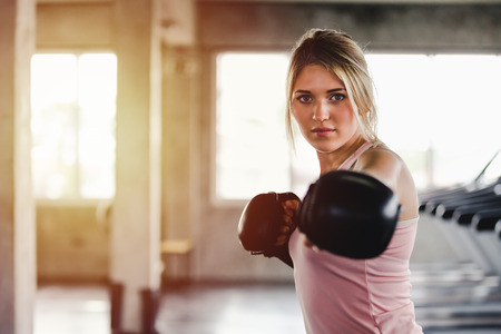 Portrait sporty girl beautiful woman with the back boxing gloves training at the gymの写真素材