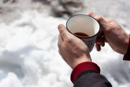 A cup of coffee in man's hands in winterの写真素材