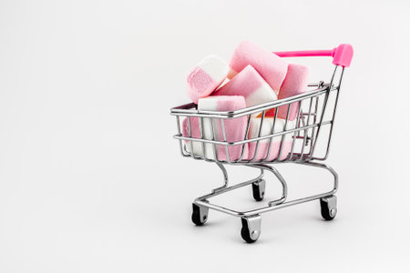 Shopping cart with pink and white marshmallows on white backgroundの写真素材