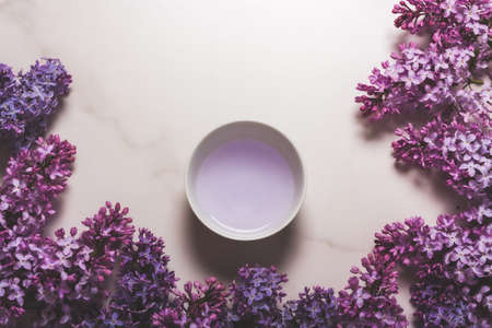 A bowl on a marble background decorated with lilac flowersの写真素材