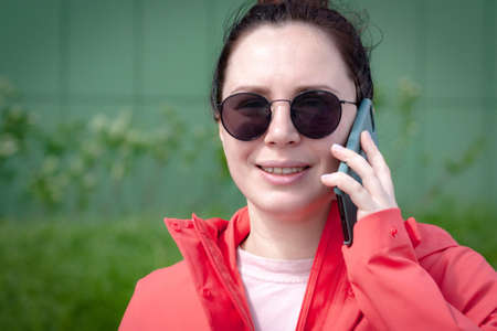 Young woman in sunglasses talking on mobile phone outdoors