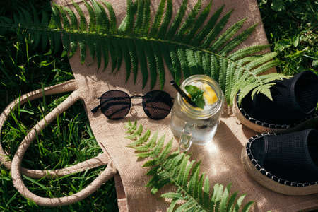 Summer flat lay. Sunglasses, sandals and lemonade in glass on the grass.の写真素材