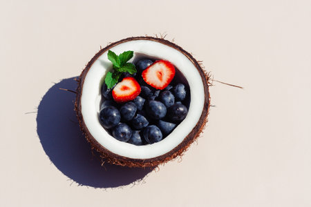 Half of coconut full of berriesの写真素材