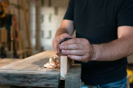 Carpenter working with plane on workbench