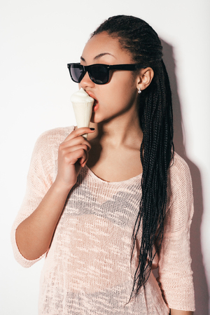 Gorgeous young girl eating cake. Posing in the studio on a white backgroundの写真素材