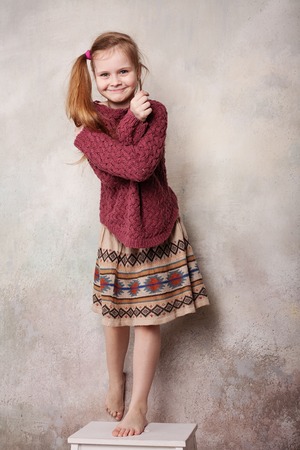 Little girl fooling in the studio, hamming, posing, having fun, enjoying life, carefree childhoodの写真素材