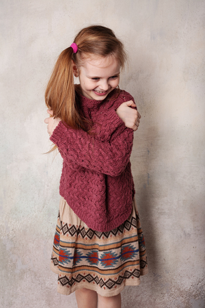 Little girl fooling in the studio, hamming, posing, having fun, enjoying life, carefree childhoodの写真素材