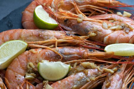 fried langoustine with lime and garlic on a black plateの写真素材