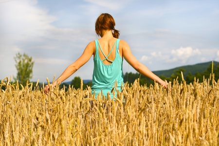 Girl walking trough the golden wheat field.の写真素材