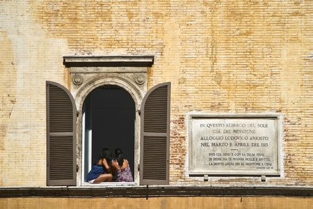 Two italyan girls sitting on the window shelf のeditorial素材