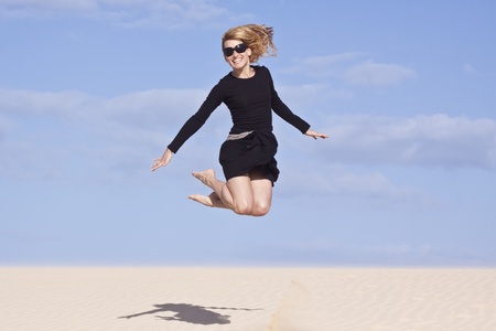 Beautifull girl jumping on the sand dune.の写真素材