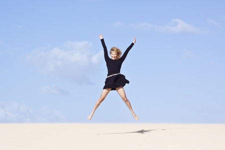 Beautifull girl jumping on the sand dune.の写真素材