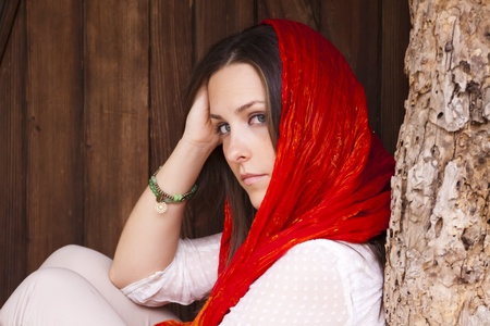 Young attractive woman portraited siting infront of the wooden doors.