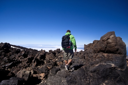 Man hiking. Young  guy hiking / backpacking in the rough  volcanic landscape on the volcano, Teide, highest peak of Spain.の写真素材